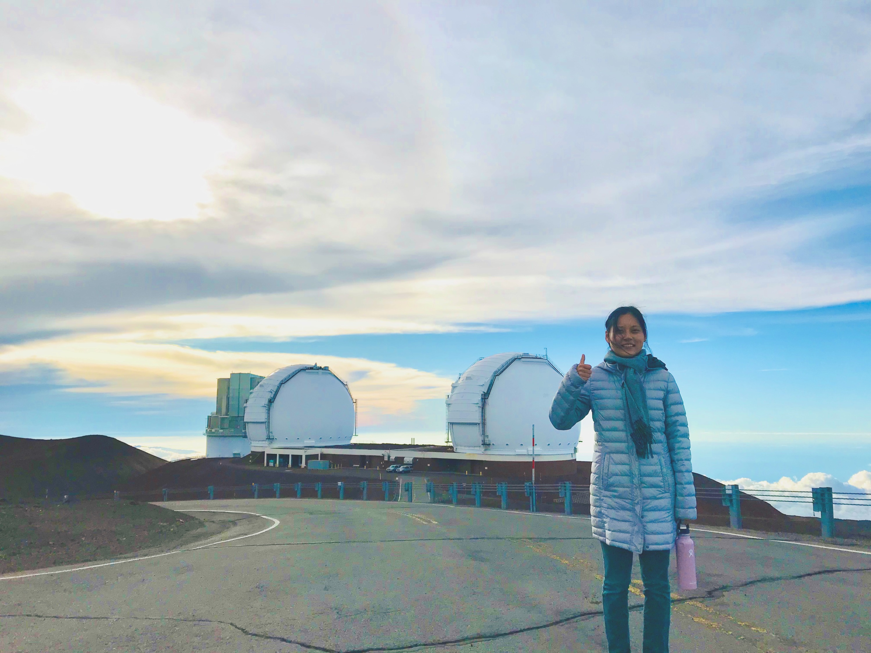 Jingwen standing near observatory domes on Maunakea.